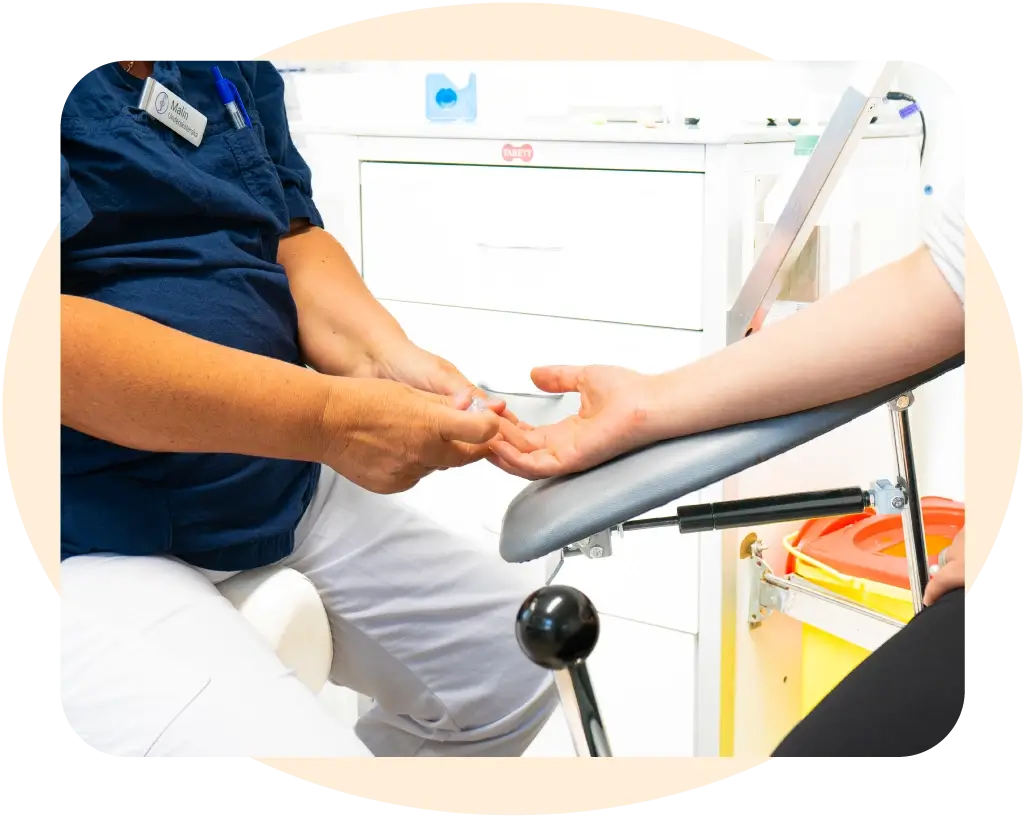 diabetessköterskemottagning. En diabetessköterska som tar ett blodprov från en patients finger