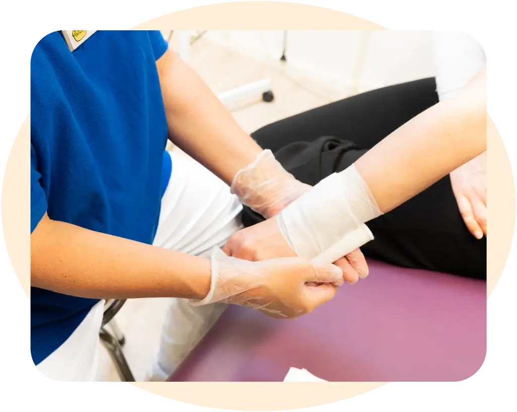 En distriktssköterska lägger om ett bandage på en patients handled. distriktssköterskemottagning