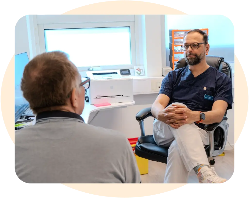 En läkare sitter och lyssnar på en patient. Läkarmottagning