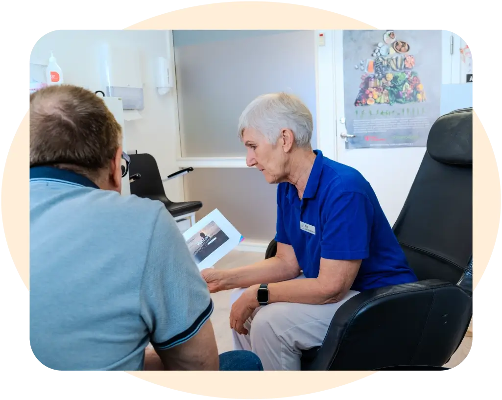En distriktssköterska sitter och pratar med en patient. livsstilsmottagning